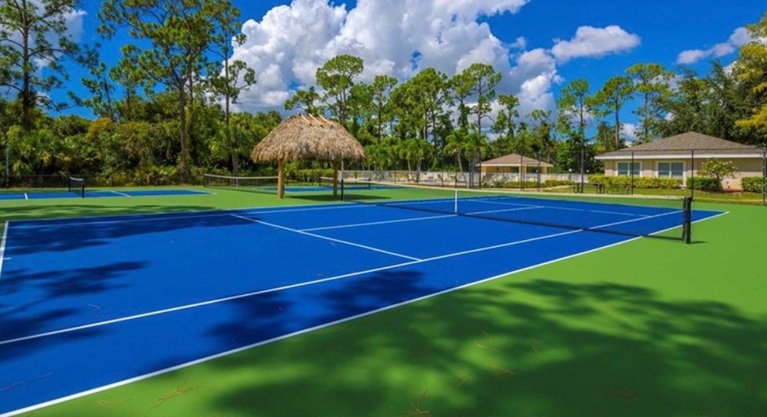 This image depicts a luxurious single-family home situated in a desirable gated community, featuring a private pool and a screened lanai that overlooks a serene lake. The spacious open floor plan allows for abundant natural light, creating an inviting atmosphere for outdoor living and relaxation.