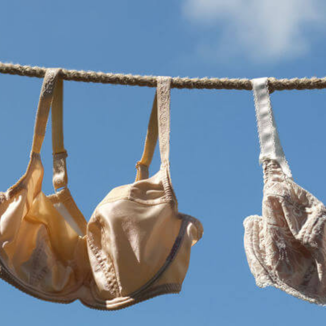Supportive bras with structured cups and wide straps hanging on a clothesline