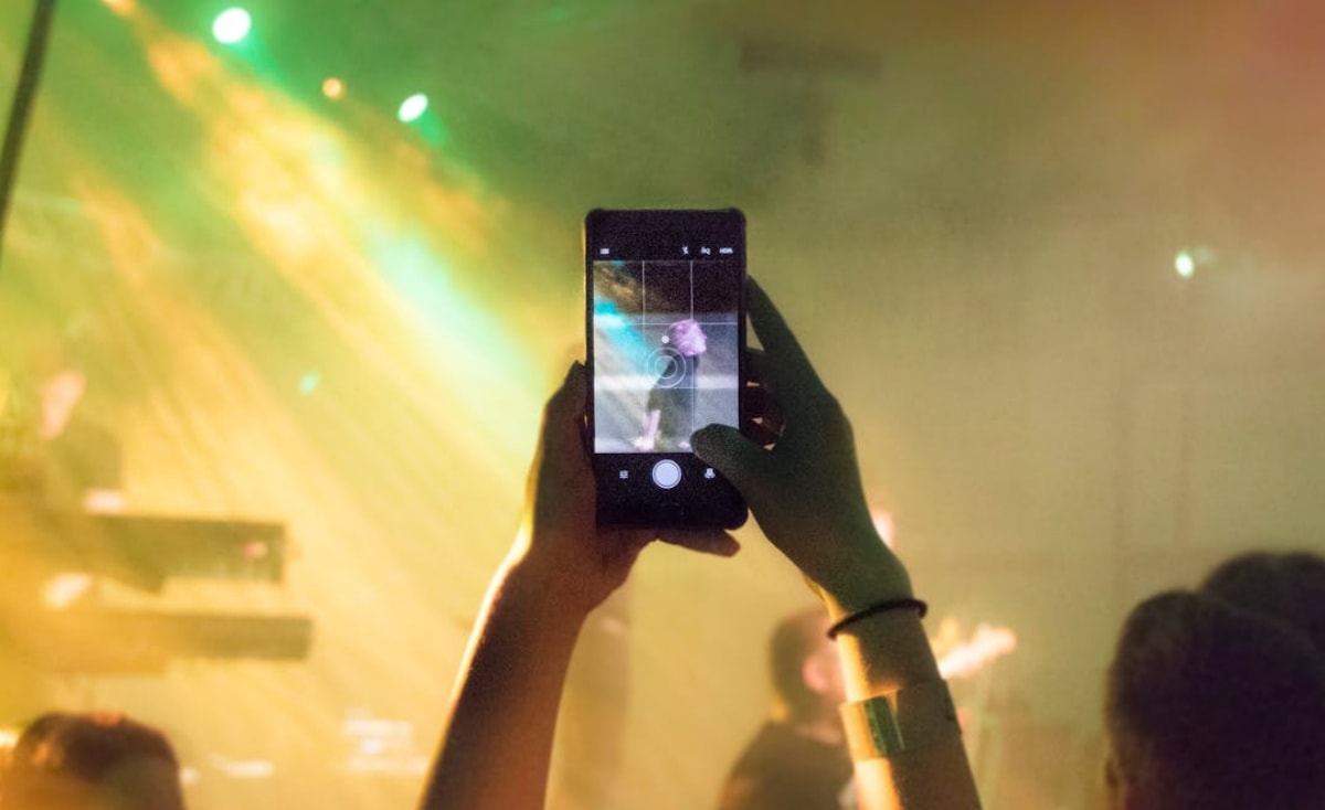 Person taking a photo on a smartphone at a concert