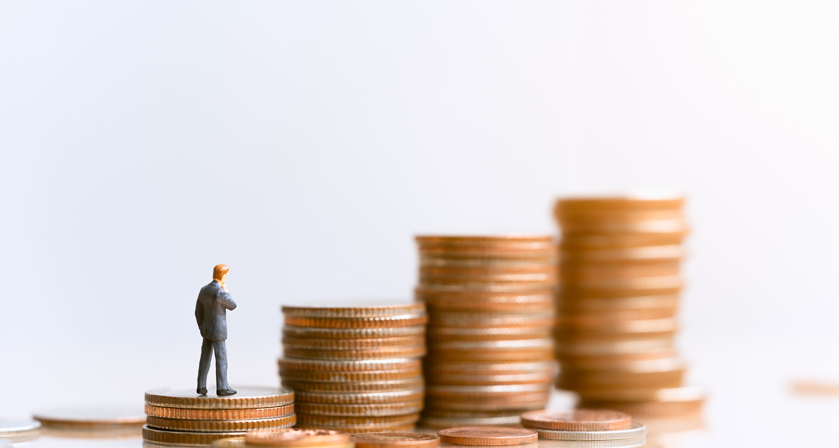 A plastic figurine climbs up a pile of coins