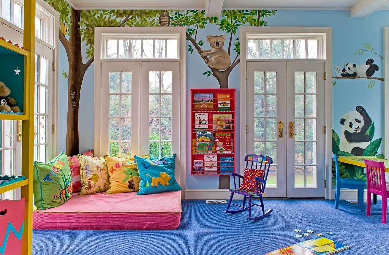 A cosy reading nook is set up in a toddler room, featuring soft cushions and a selection of colourful books displayed at toddler height, inviting young children to explore and enjoy reading in a playful and imaginative space.