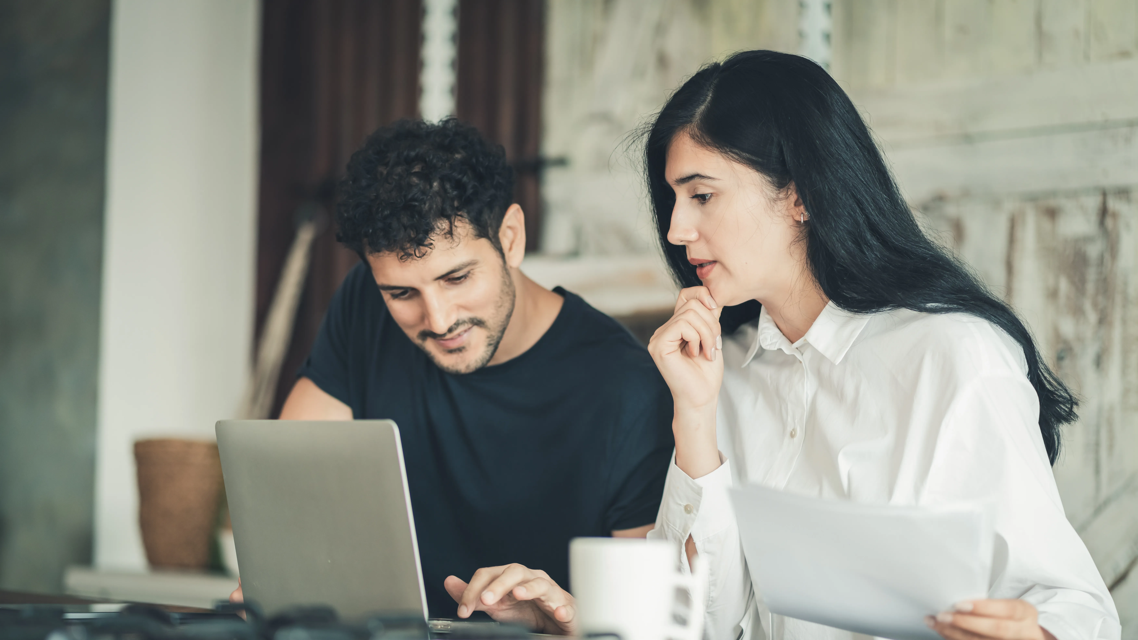 Small business owners planning website development goals together on a laptop, discussing whether to build an online store, lead-generation site, or professional business website.