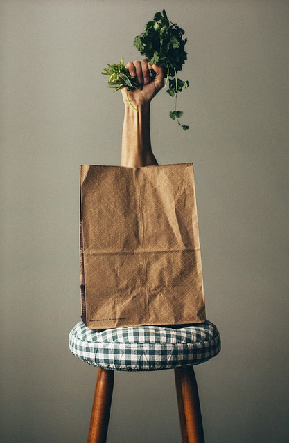 brown grocery bag with hand sticking out holding organic beets and vegetables