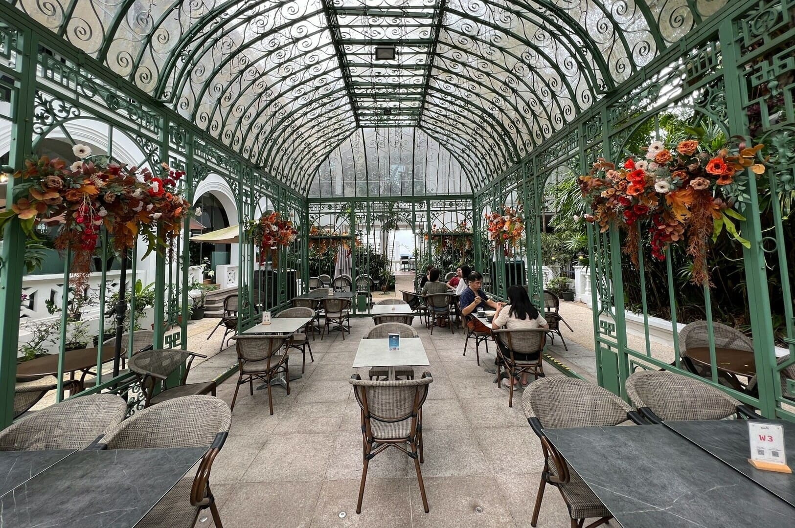 A view of the greenhouse in Singapore's botanical gardens, featuring lush plants and a nearby restaurant setting.