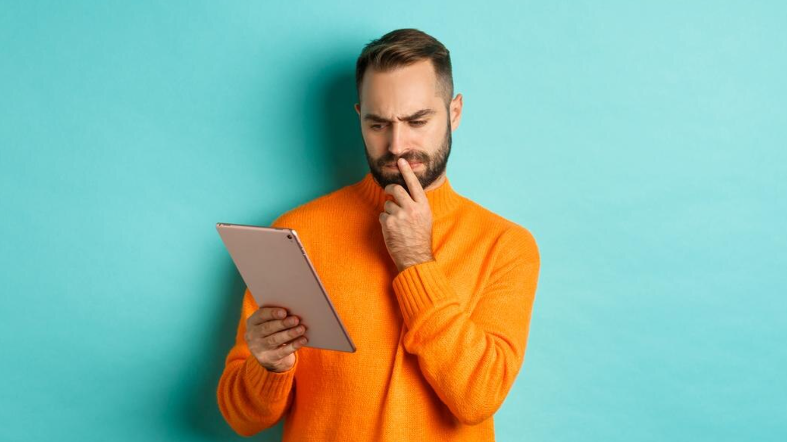 Man in orange sweater looking puzzled at a tablet, representing confusion about Operator Connect Certification.