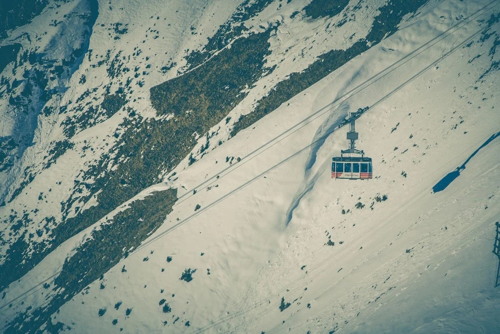 cable car against mountain summits with snow