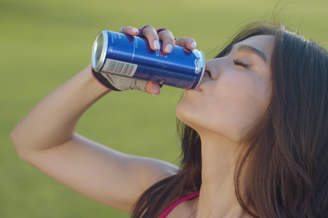 Woman drinking a functional energy beverage outdoors for boosting energy and wellness