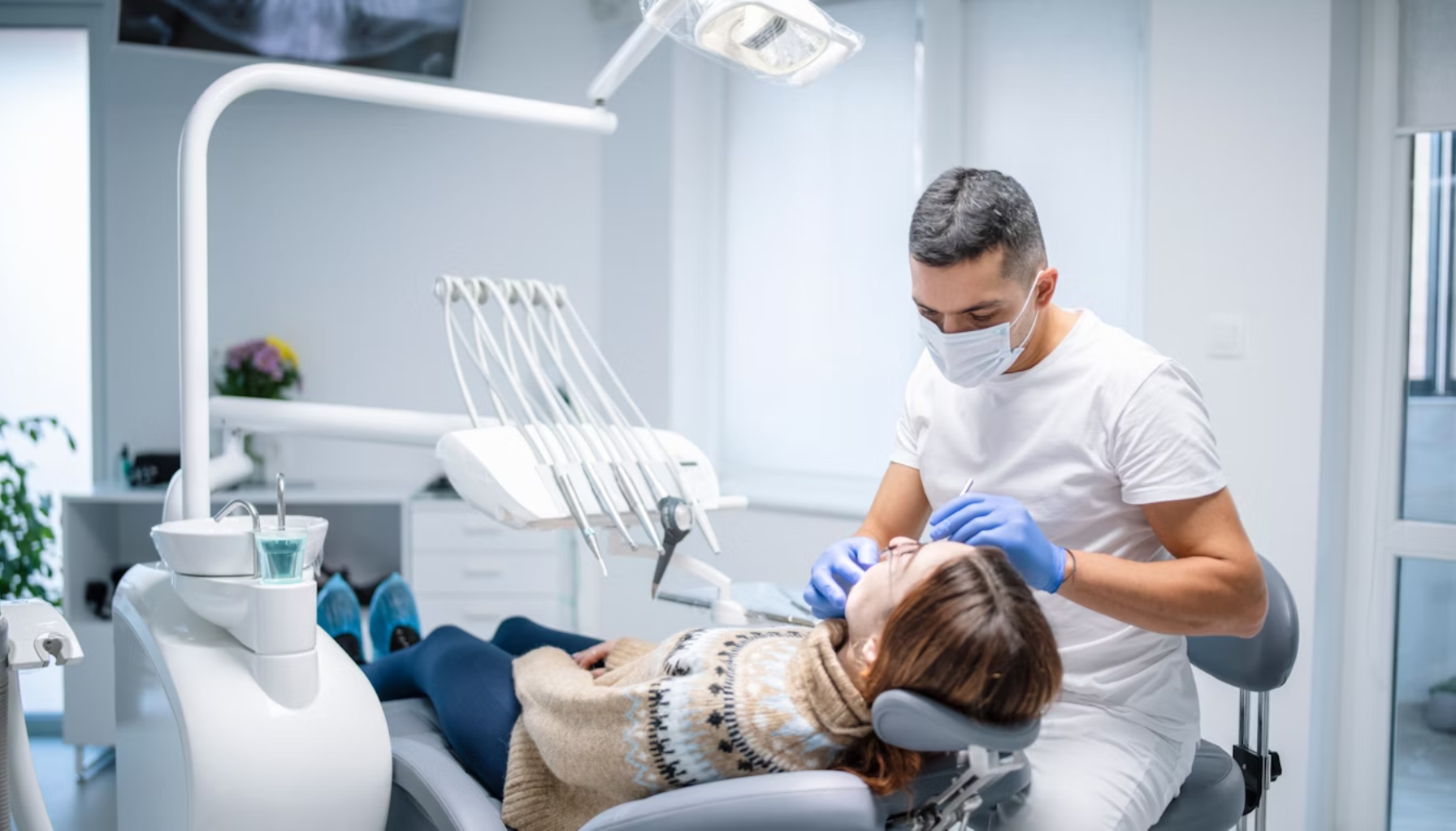Tannspesialist på Eiksmarka – Når trenger du én? 18 Tannlege med munnbind og hansker behandler kvinnelig pasient som ligger i tannlegestol, omgitt av moderne utstyr i en lys klinikk.