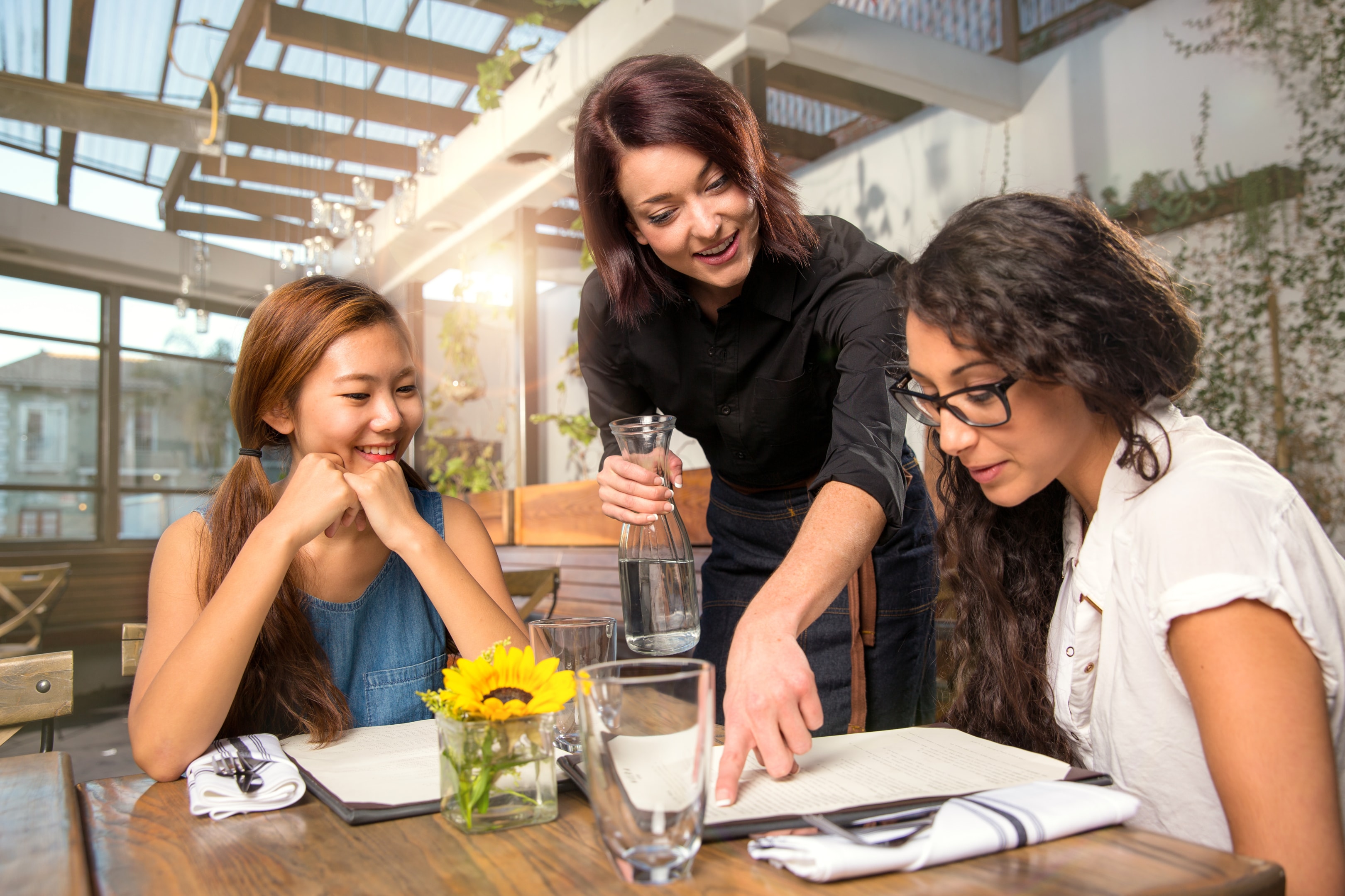 A restaurant server helps a guest with menu questions