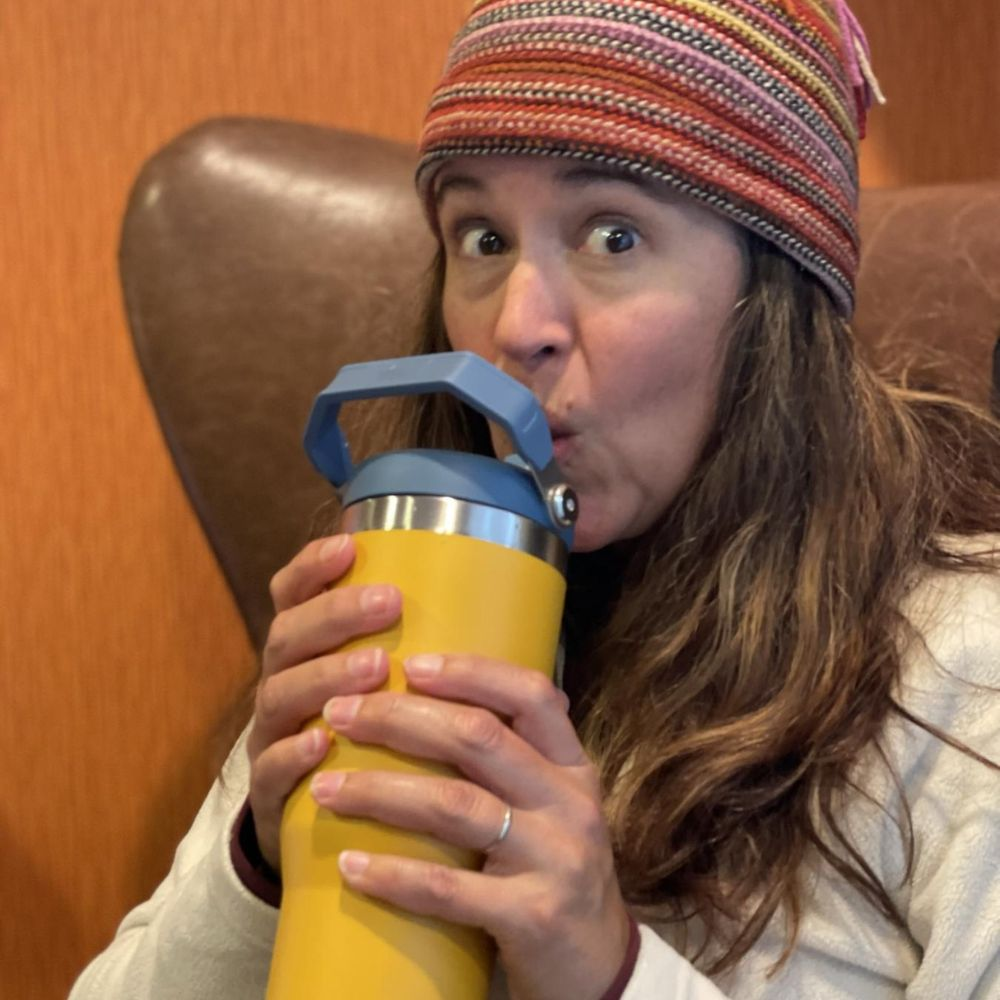 A person drinking directly from a Stanley tumbler without a straw, demonstrating the can you drink out of a Stanley without a straw feature.