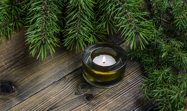 A candle among green Christmas reefs on a wooden table
