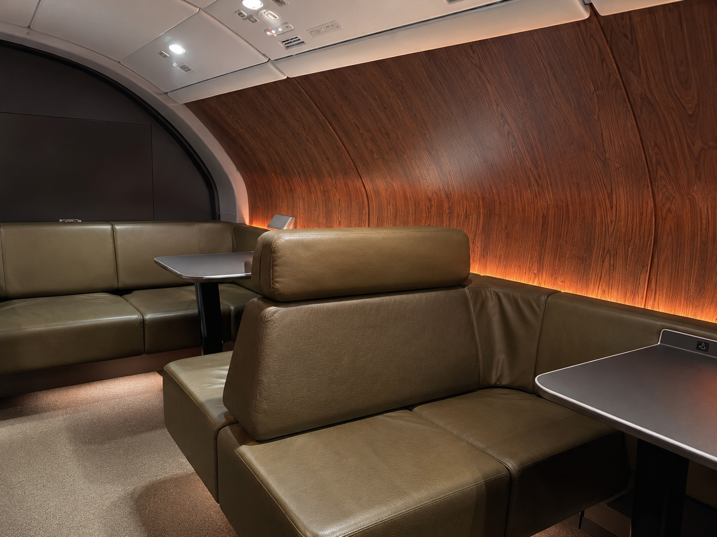 Qantas A380 upper deck lounge with leather seating, wood-paneled walls, and small tables for business class passengers.