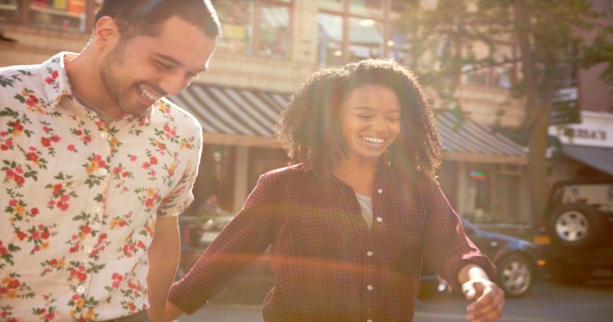 A photograph of a couple walking hand in hand down a busy street in New York City, smiling and appearing happy and content. The image conveys the idea of a couple who have successfully undergone Gottman Method Couples Therapy and have emerged with a stronger emotional connection and greater intimacy. The couple appears happy and in love, indicating that therapy has helped them overcome previous conflicts or difficulties in their relationship. The image suggests that seeking the services of a certified Gottman Method Couples Therapist in New York City can provide couples with the tools and techniques needed to improve their relationship and live happier, more fulfilling lives together.