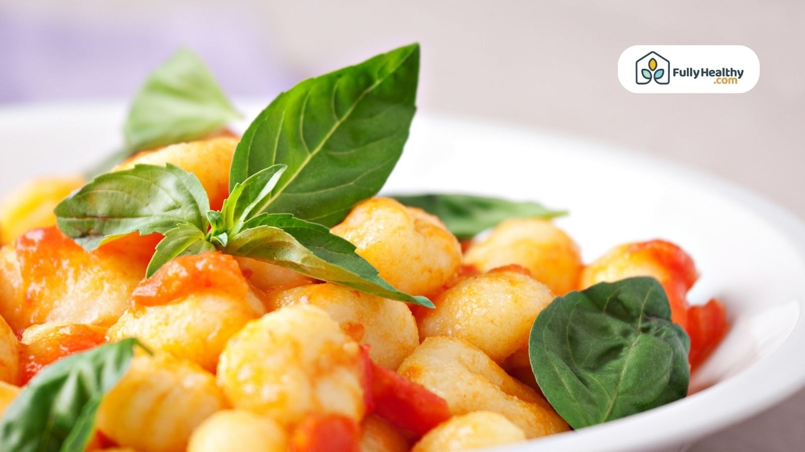Plate of gnocchi with tomato sauce and fresh basil leaves as garnish