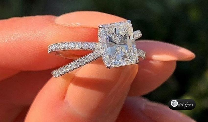 A close-up view of a stunning Princess Cut Diamond ring showcased on a finger, with the diamond set in a modern double band encrusted with smaller diamonds, highlighting the gem's pristine square shape and brilliant facets.