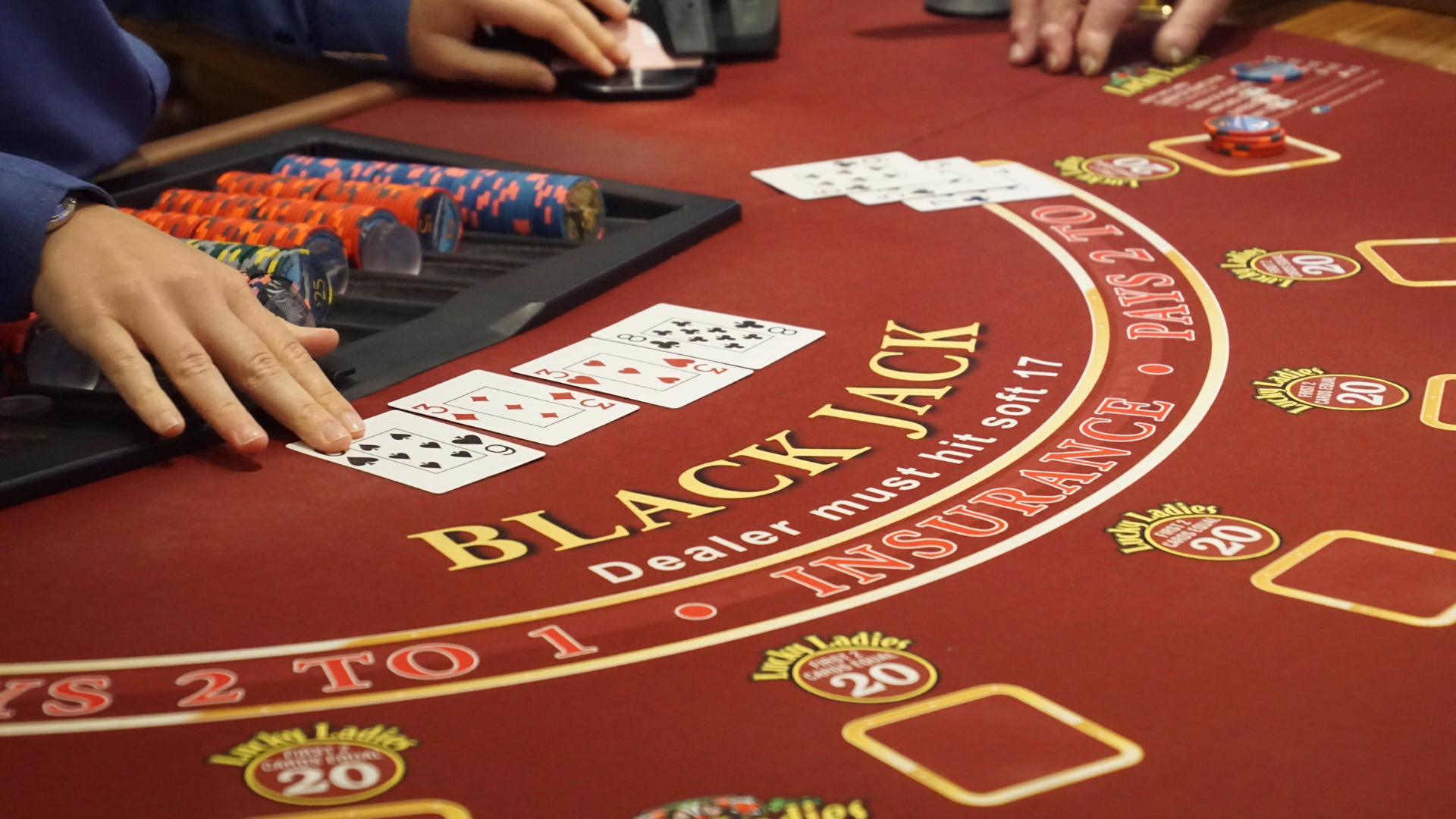 Blackjackbord med marker och spelkort under pågående hand på casino med fokus på strategi och låga odds.