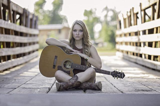 female beginner guitarists sitting with guitar on bridge