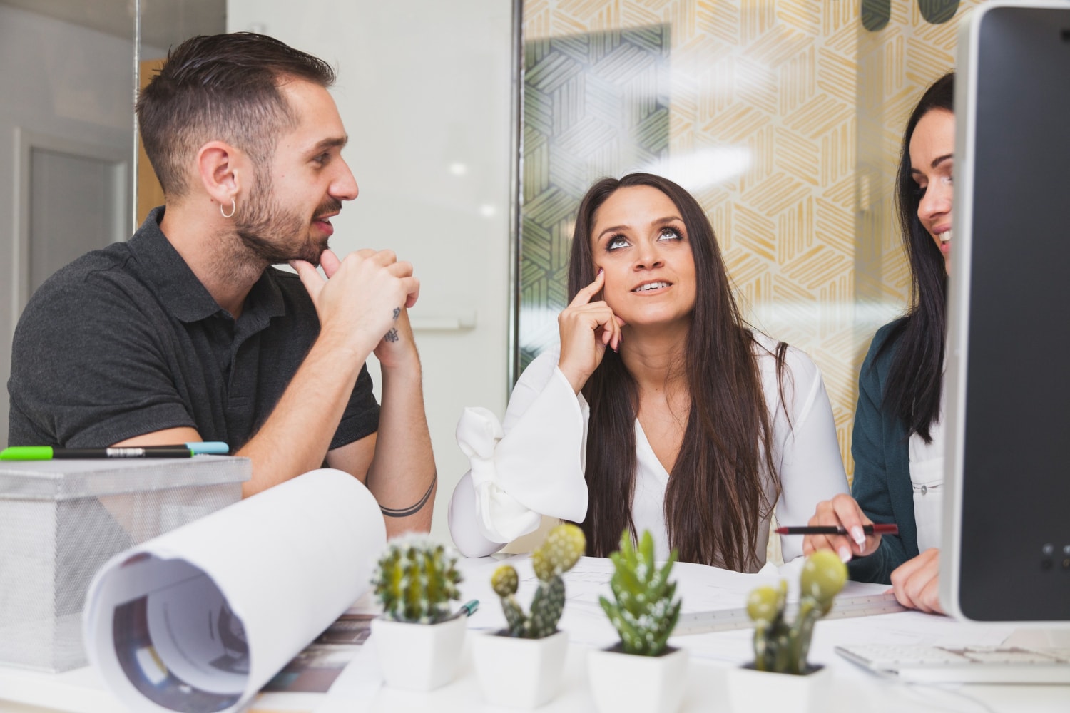 Team of coworkers engaged in a creative discussion at a modern office desk, emphasizing the role of unified communications and VoIP for business in fostering collaboration and idea-sharing.