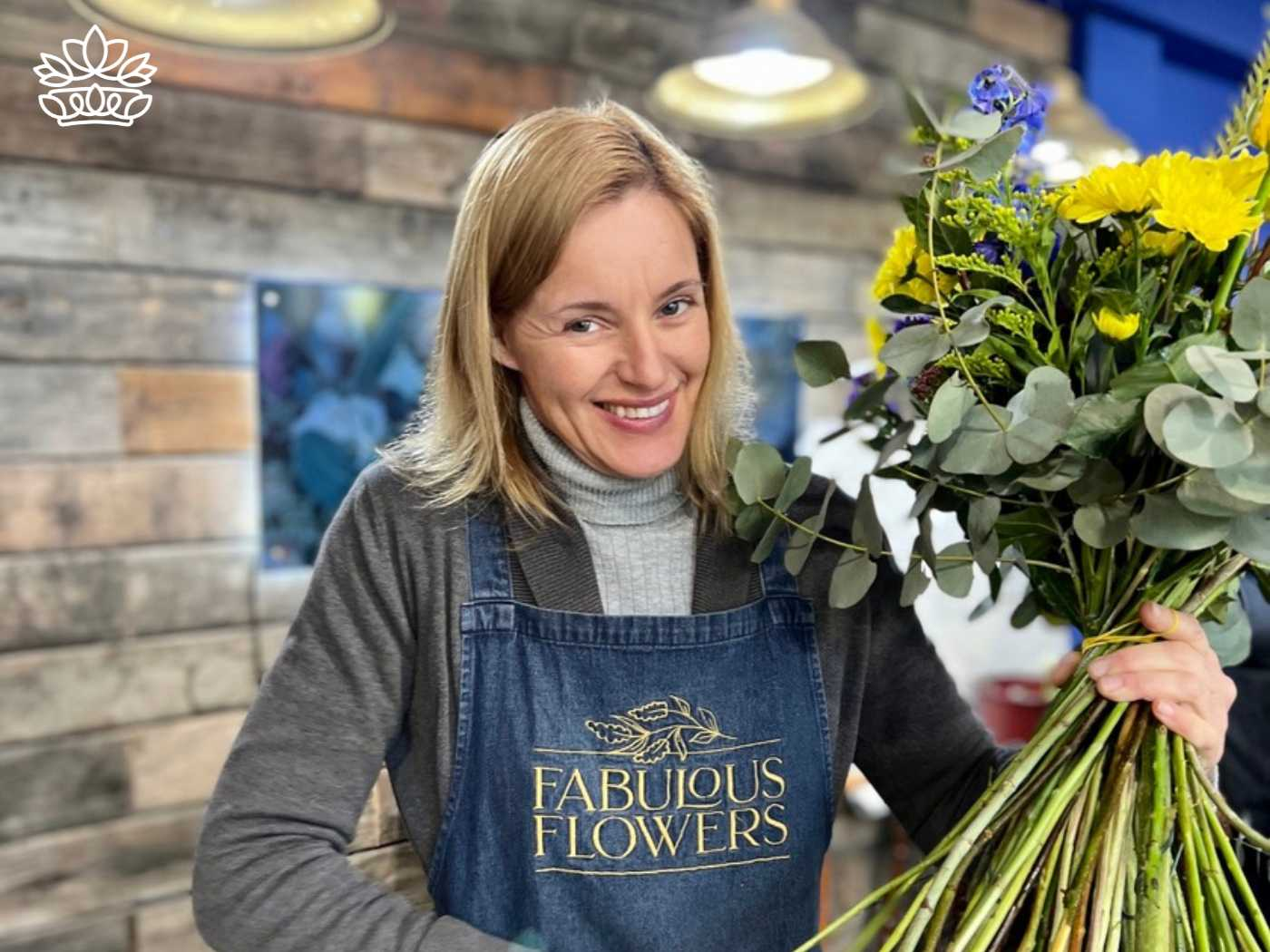 Smiling florist holding a beautiful bouquet from the Flowers By Type Collection at Fabulous Flowers and Gifts, featuring a mix of flower and seeds