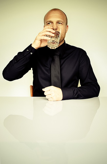 An image of a man drinking water, which can provide throat congestion relief as one of the benefits of staying hydrated.