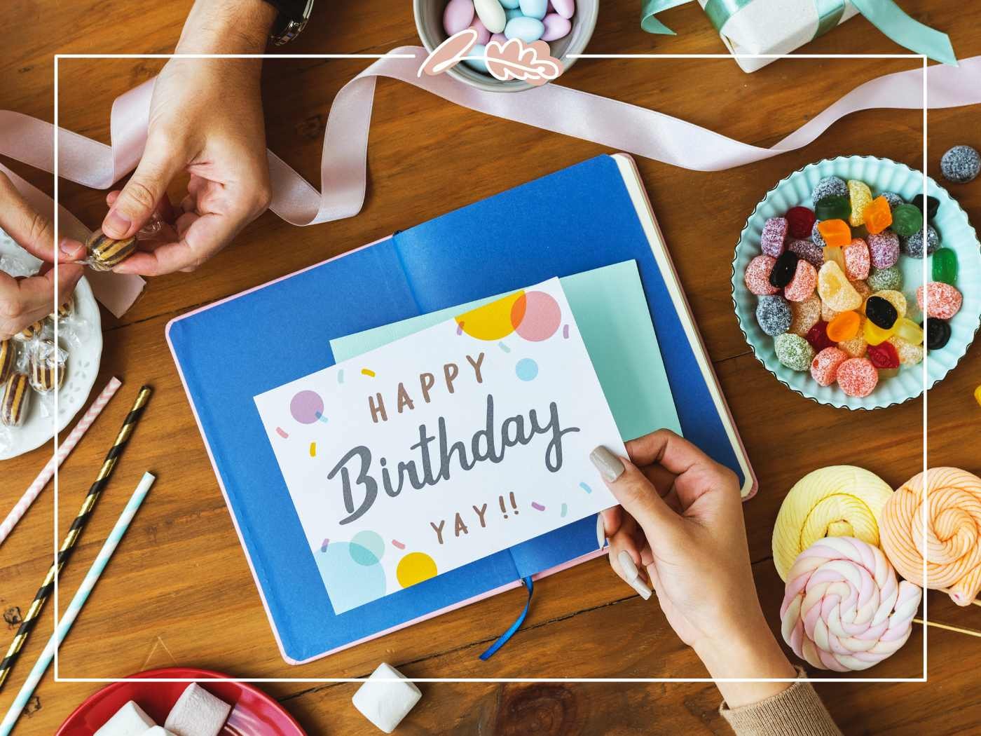 Birthday Wish for Boyfriend – hands holding a “Happy Birthday” card on a gift-ready table with sweets, ribbons and party treats