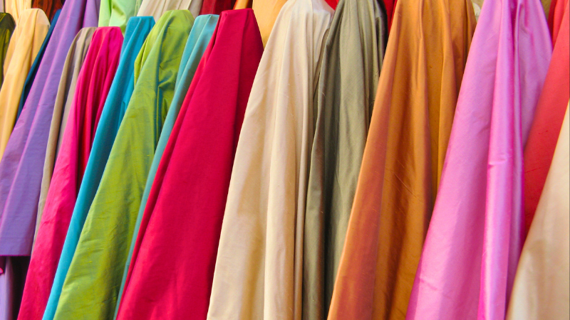 A row of colorful rayon and cotton fabrics hanging on a rack