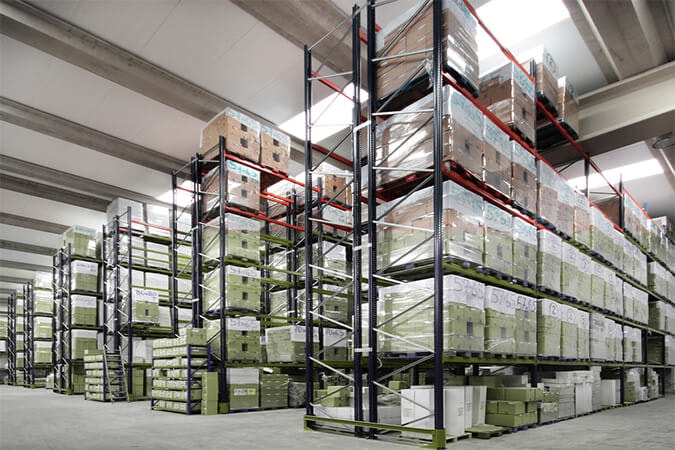 "High-capacity warehouse with multi-tier pallet racking systems and organized pallet storage of boxed goods for streamlined logistics and inventory management"
