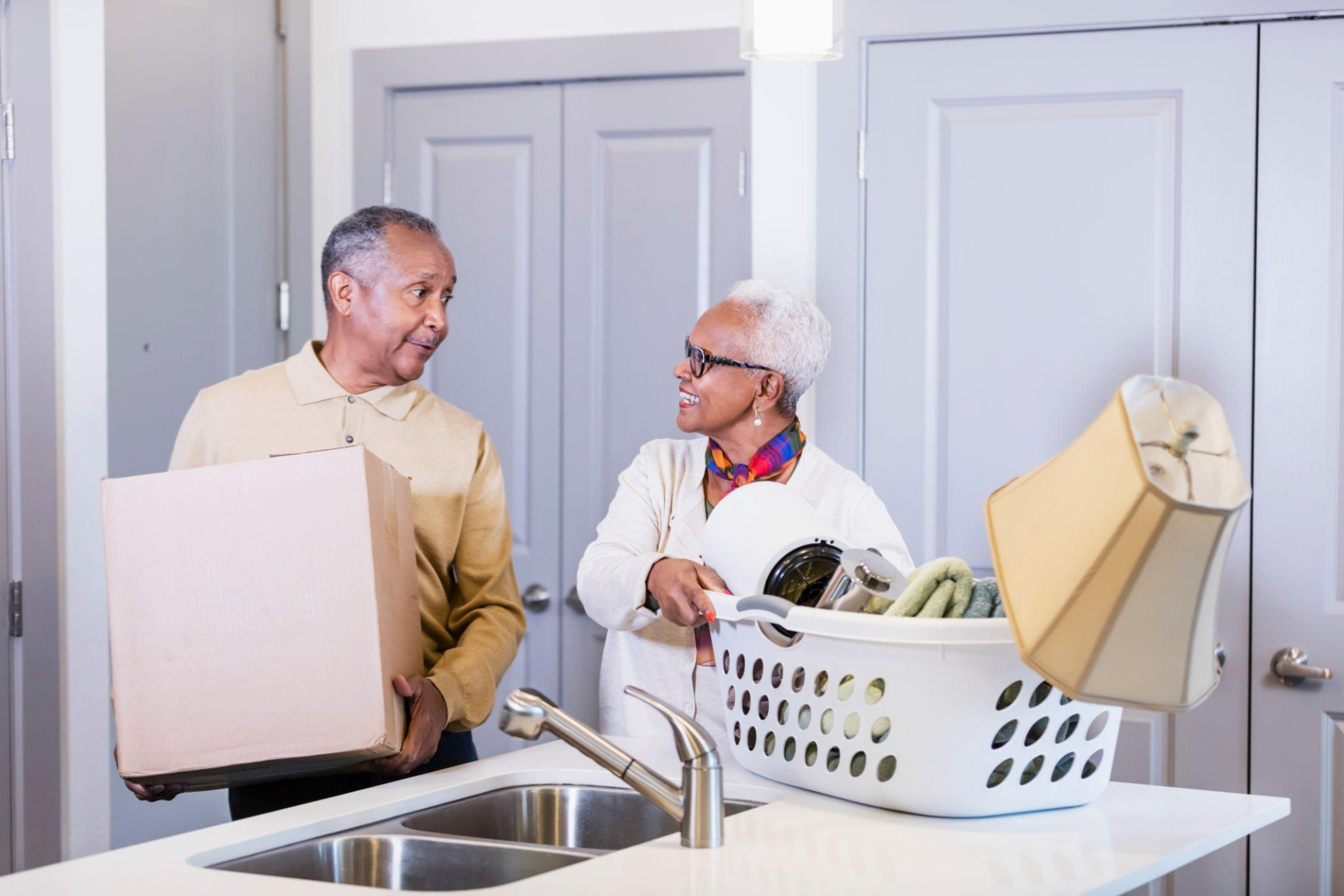 A couple holding boxes, moving into their new house; the psychological and physical stress of relocation and its potential impact on the body's metabolism chronic stress.