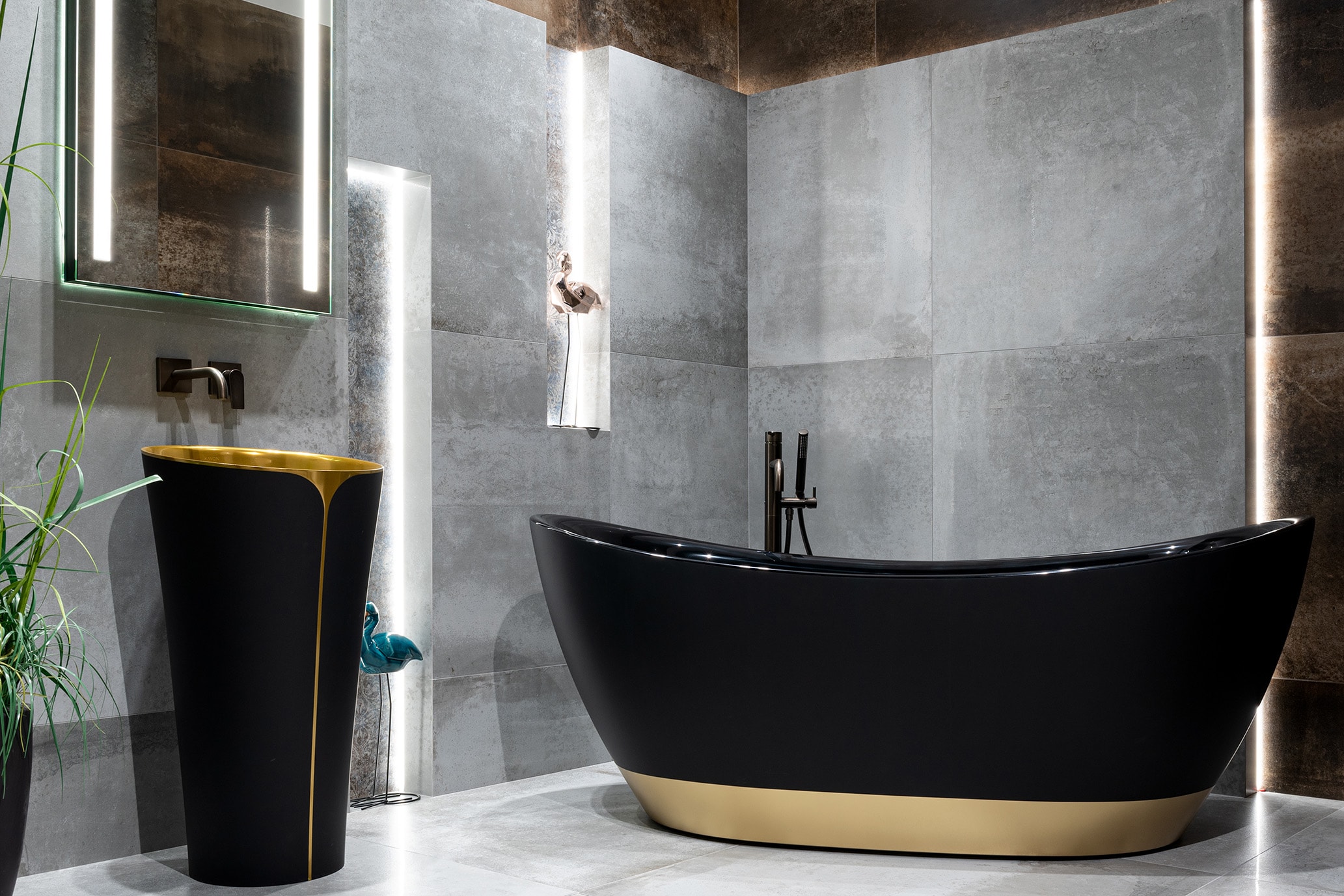 Płytki imitujące beton zestawione z czarno-złotą armaturą w nowoczesnej łazience.