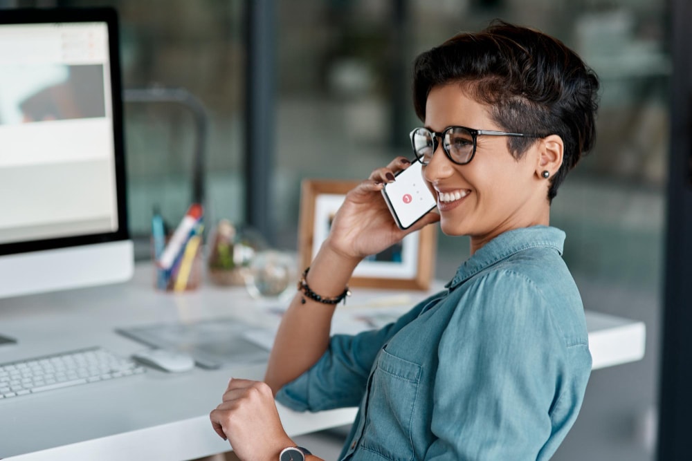 Business woman using a cloud phone system phone through her cellphone in office.