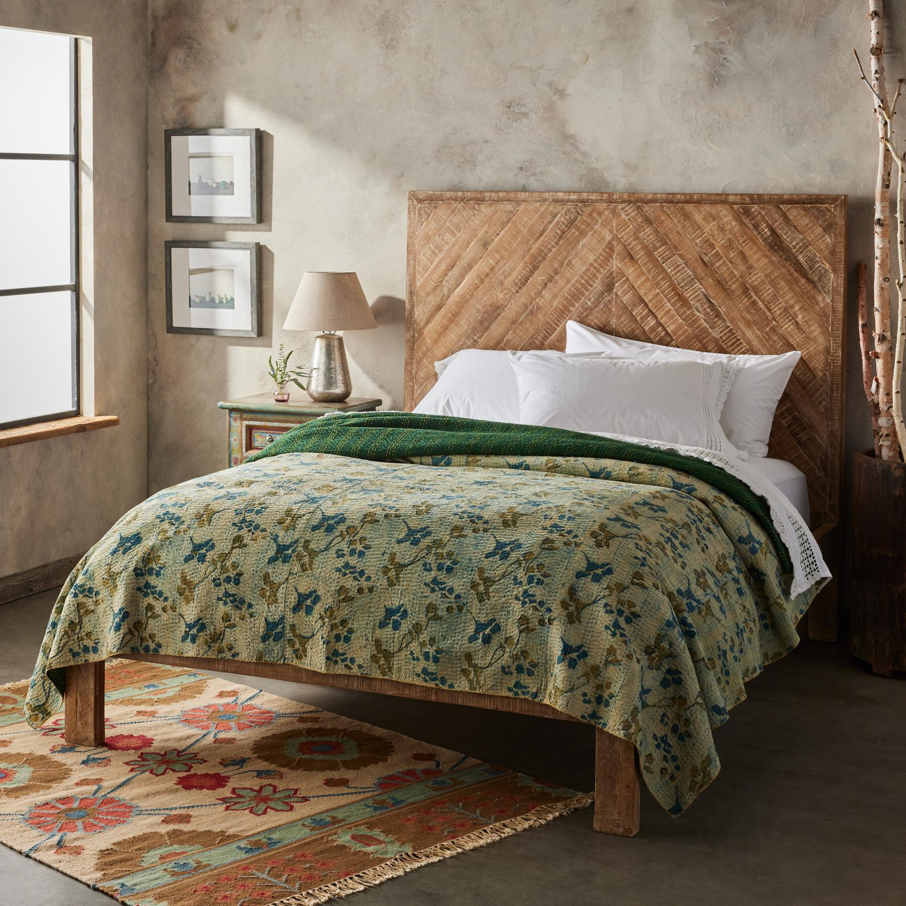 green bedding on wood bed with fringe rug