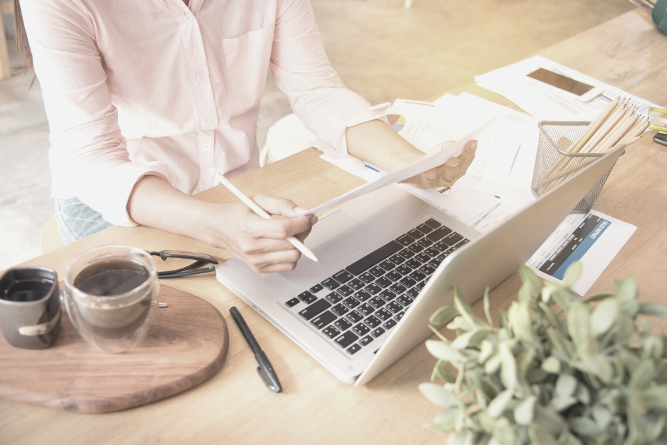 woman sits at a desk with coffee and laptop to complete a content audit