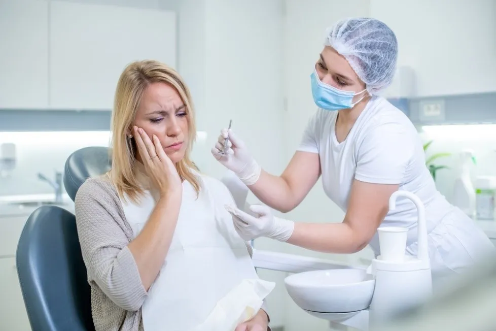 Kvinne med tannsmerter hos tannlegen som får behandling og råd i en moderne tannklinikk. 