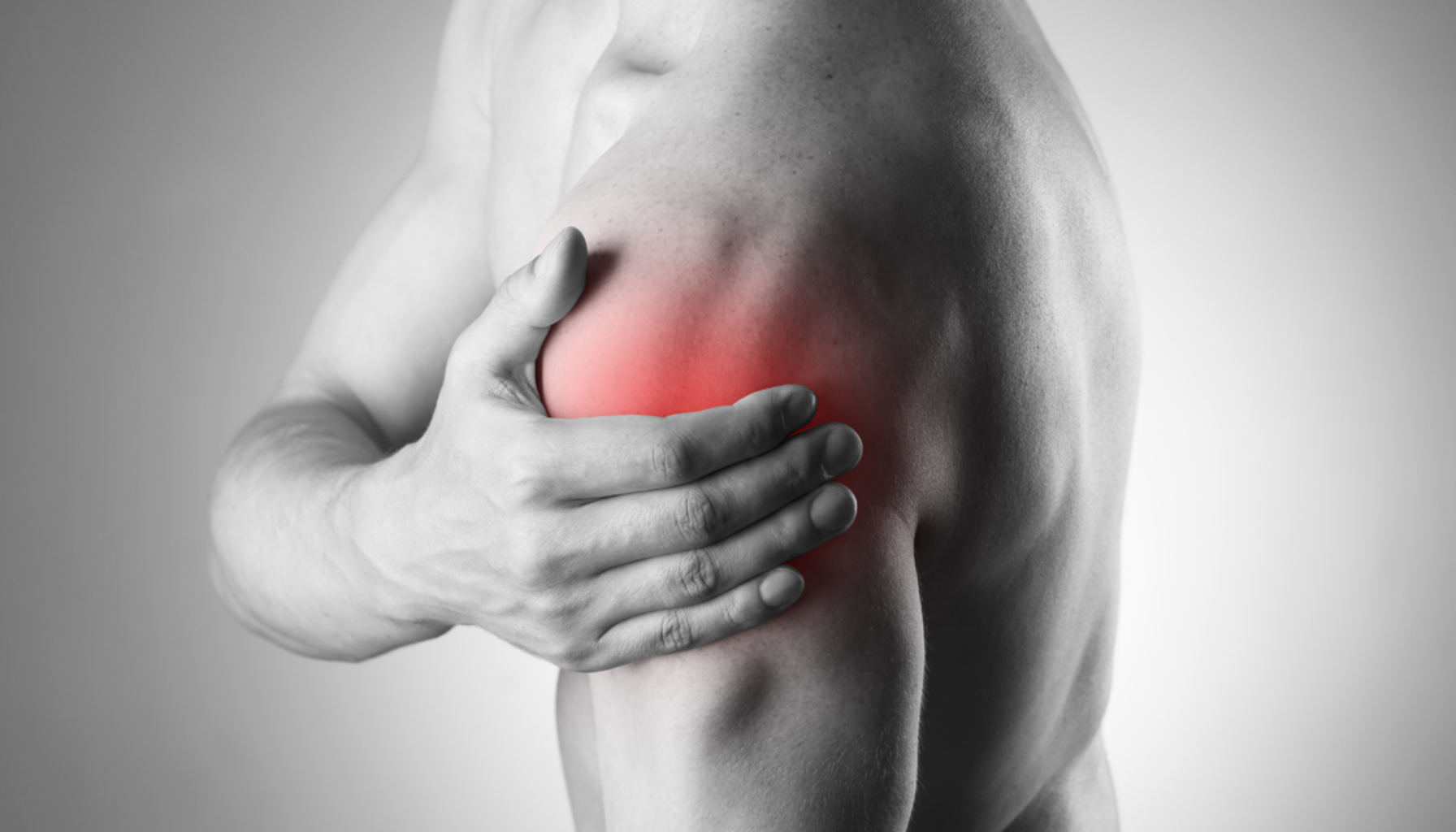 En mann holder hånden på skulderen med tydelig smerte, rødlig område markerer betennelse eller skade.