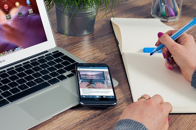 person writing on a desk referring to keyword research tools to help search engine optimization and search results