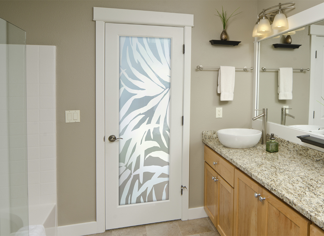 A bathroom with a frosted glass door featuring a tropical design.