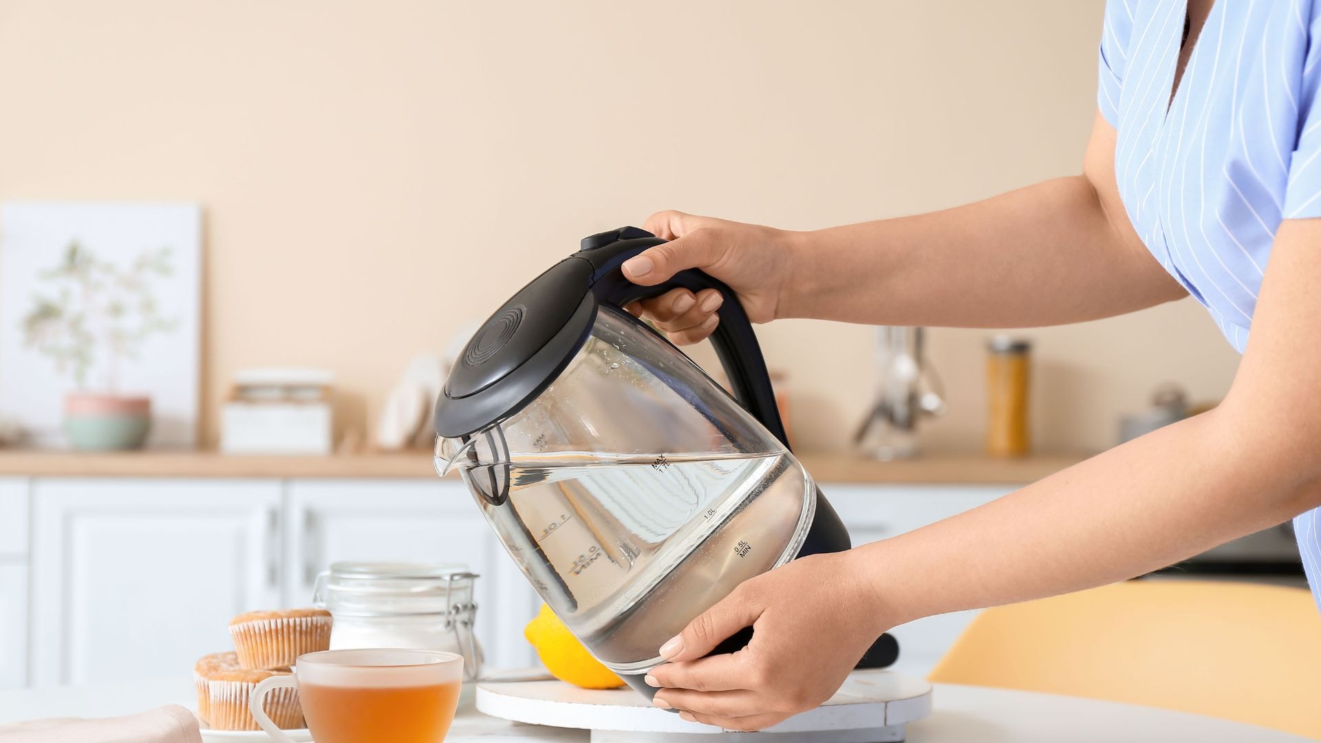 Kobieta nalewająca ciepłą wodę z czajnika do szklanki