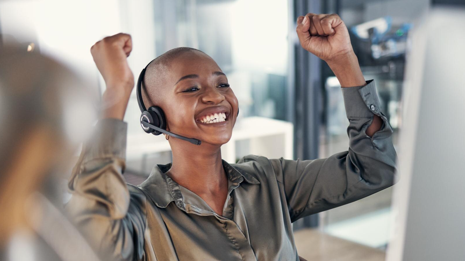 Smiling woman in headset raising arms in victory, celebrating the positive impact of becoming an operator connect partner through TeamMate.