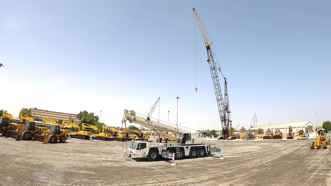 Spacious construction equipment yard showcasing various heavy machinery including mobile cranes, bulldozers, and excavators under clear blue sky