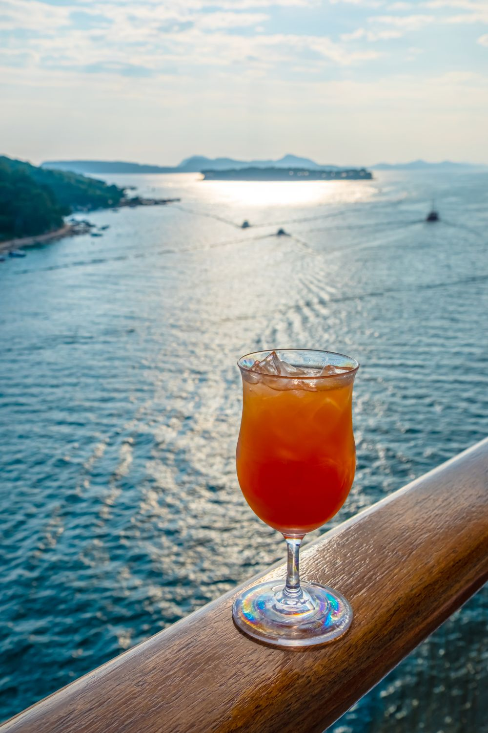 Image of a drink on a cruiship overlooking a harbor - Select drinks may be included on a carnival cruise