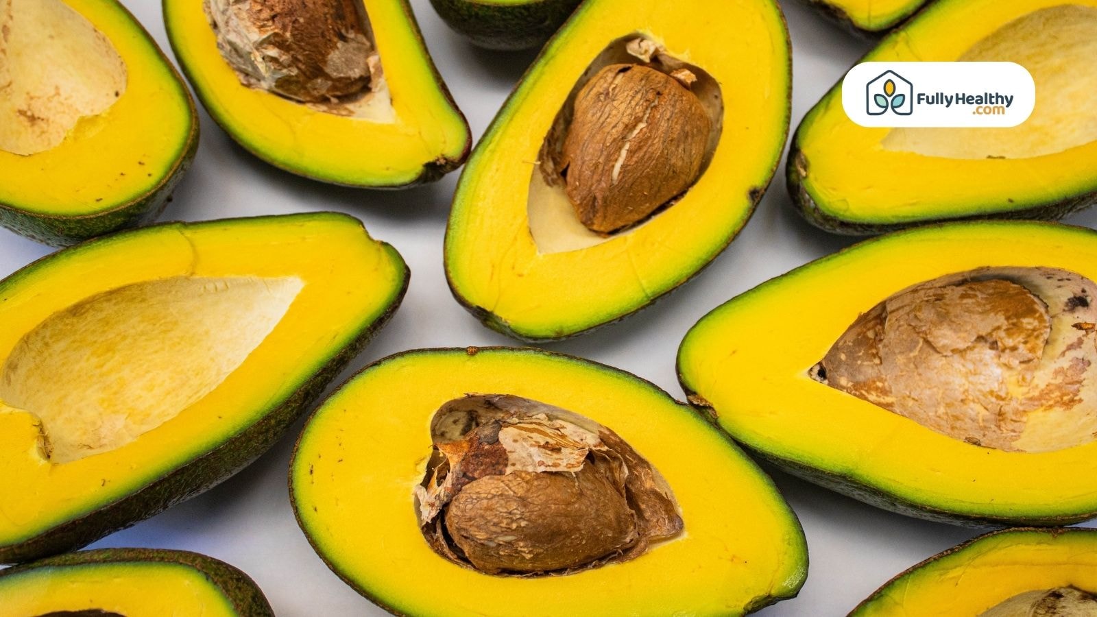 Multiple halved avocados showing pits and golden flesh
