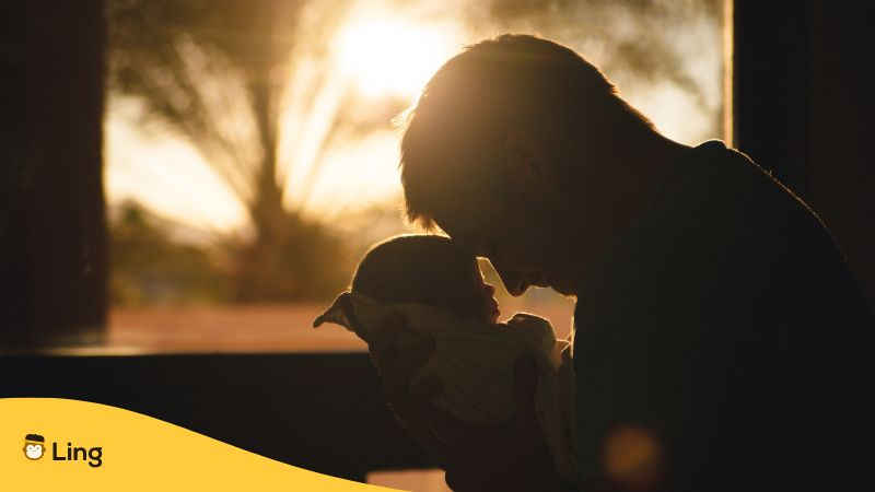 Man carrying a baby drawing their foreheads