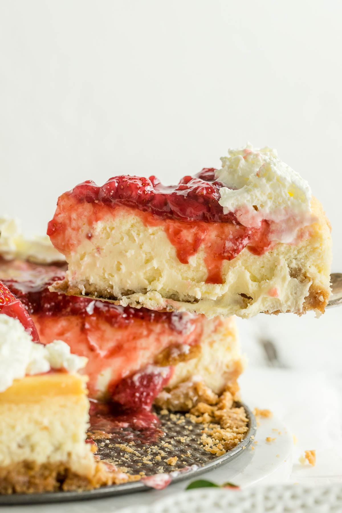 cake server holding a slice of strawberry cheesecake