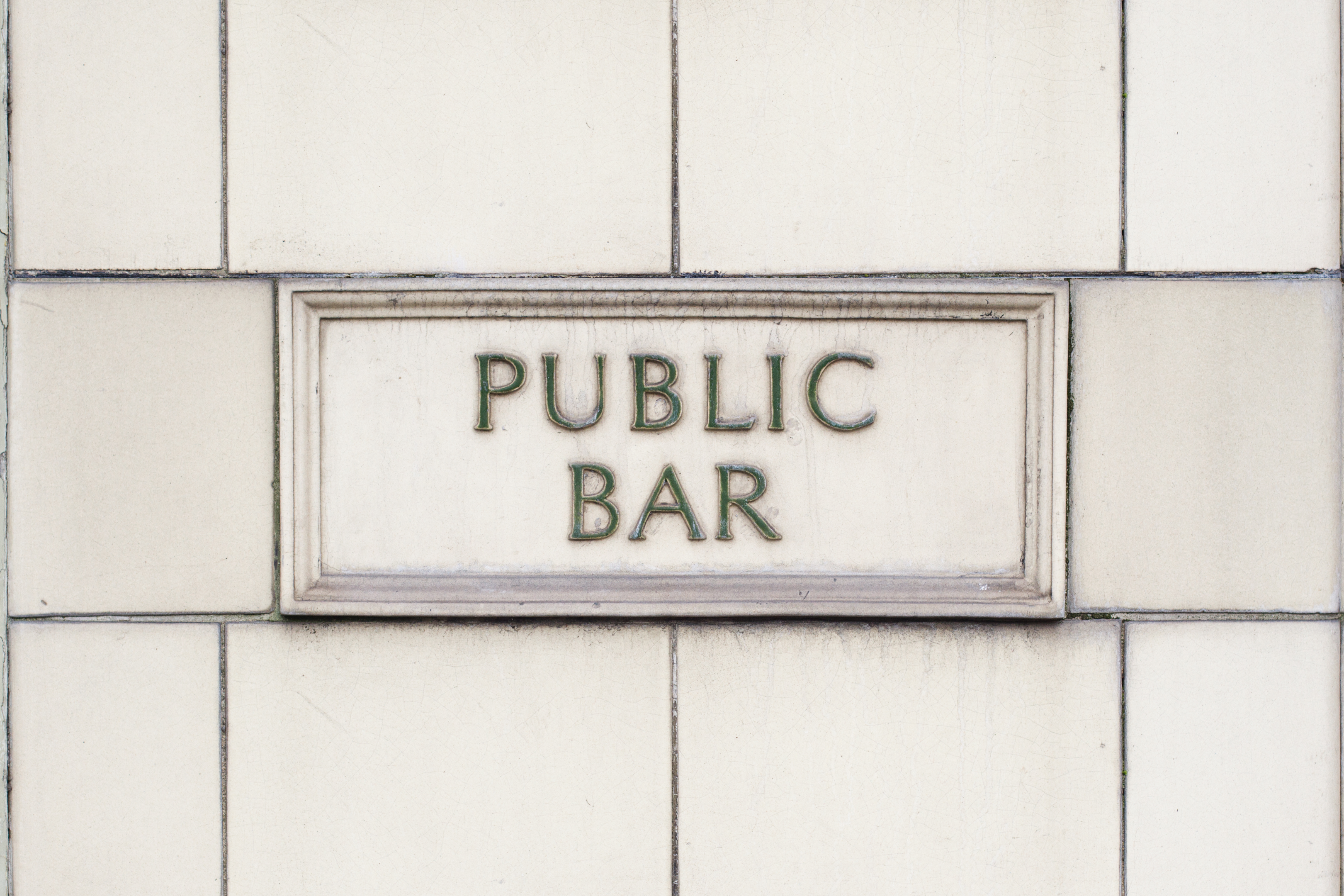 Traditional British pub sign displayed against a white brick wall.