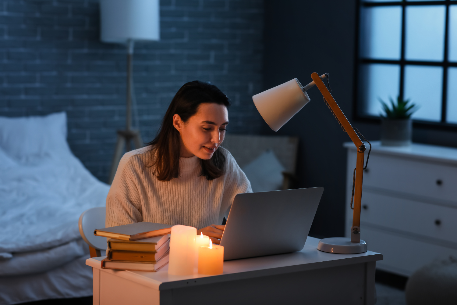 A remote worker using a laptop during a brownout, lit by candlelight.