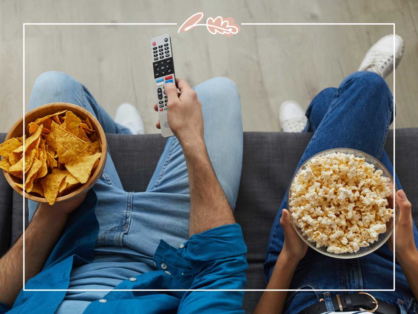 A close-up of a couple's hands holding bowls of nachos and popcorn, ready for a movie night - Fabulous Flowers and Gifts.