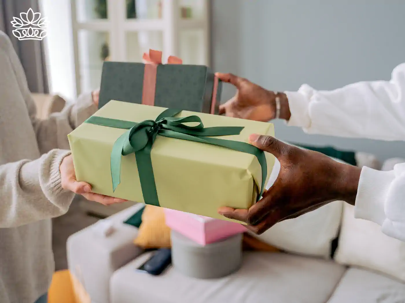 Two people exchanging a beautifully wrapped thank you gift box in a warm home setting. Fabulous Flowers and Gifts - Thank You Gift Boxes. Delivered with Heart.