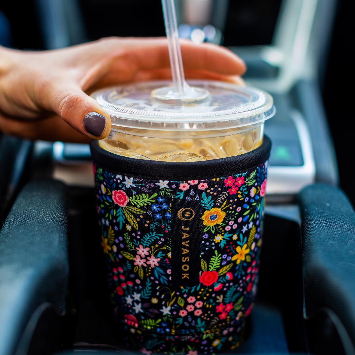 A Java Sok in the pattern English Garden on an iced coffee cup in a cup holder.