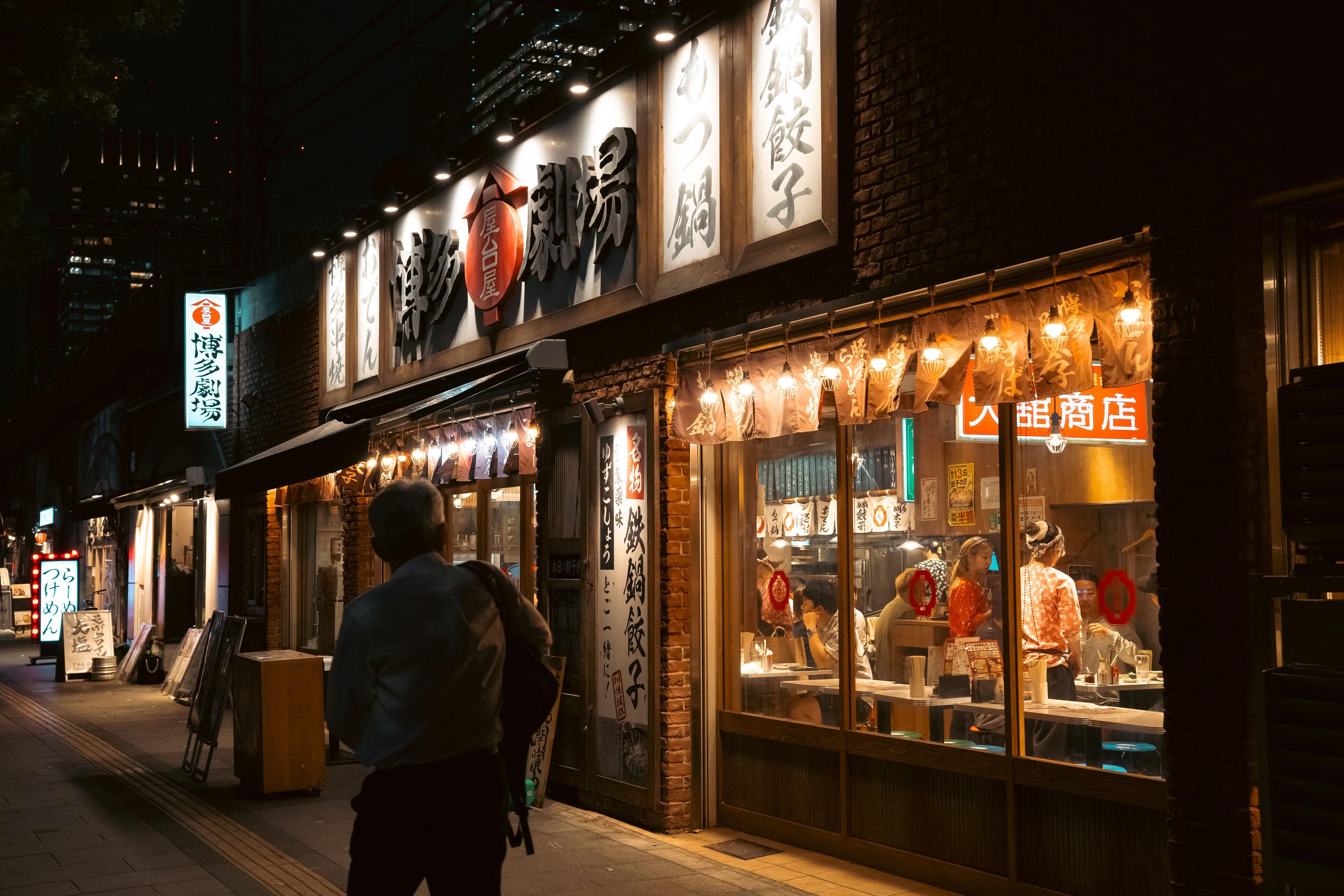 A person is walking down a bustling city street, intently using a smartphone to search for nearby restaurants, highlighting the importance of local search results and effective marketing strategies for restaurant owners to attract potential customers. The scene reflects the modern reliance on technology to enhance customer engagement and satisfaction in the restaurant industry.