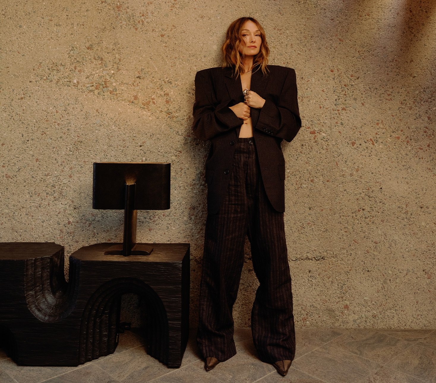 Kelly Wearstler standing next to a sculptural black table lamp from her Visual Comfort collection.
